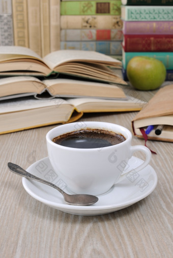 杯咖啡的表格对的背景开放书与笔记本而且堆栈书