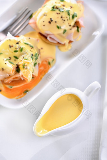 荷兰黄油酱汁肉汁船为早餐服务与鸡蛋本尼迪克特-炸英语好他挖走鸡蛋