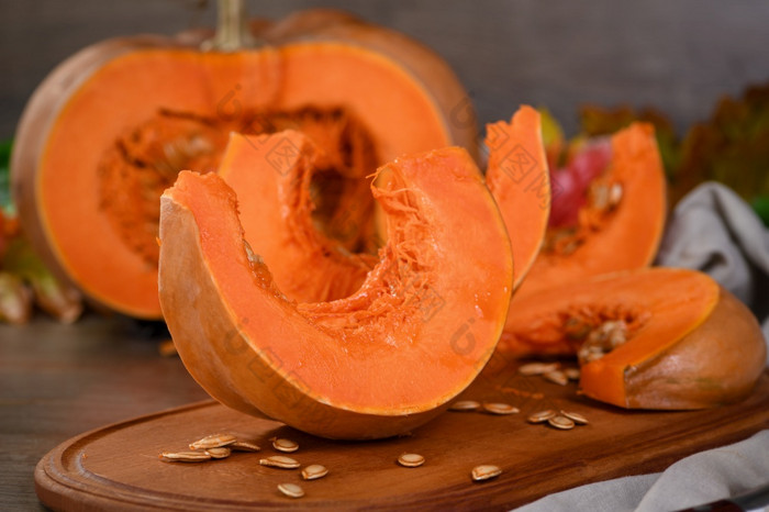整个新鲜的橙色大南瓜和片南瓜木董事会特写镜头有机蔬菜产品成分为烹饪健康的食物素食主义者