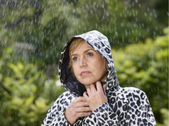 成熟的女人穿雨衣多雨的夏天一天绿色自然背景