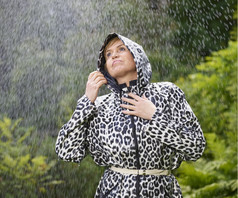 成熟的女人穿雨衣多雨的夏天一天绿色自然背景