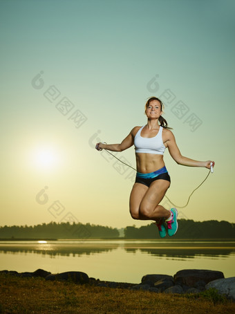 年轻的健身女人使用跳过绳子太阳而且海背景复制空间