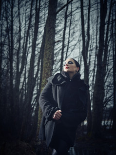 时尚女人穿冬天外套而且她构成悲观的森林冷多雨的天气交叉加工过的完整的长度图像