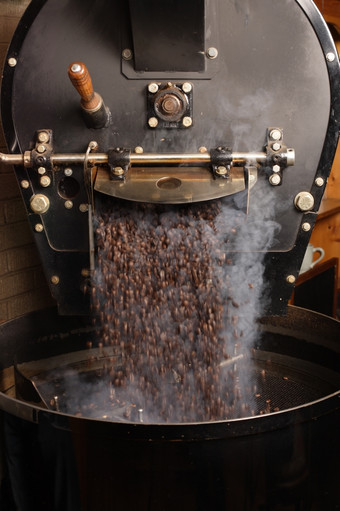 的新鲜烤咖啡豆子从大咖啡烘烤器被倒成的冷却油缸运动模糊的豆子