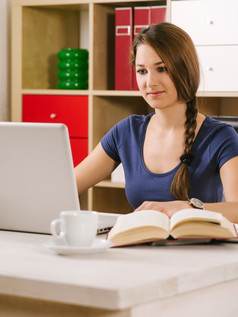 照片美丽的女人使用移动PC喝咖啡而且阅读书