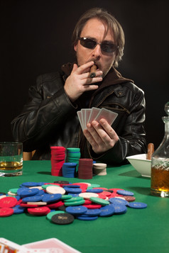 照片男人。玩扑克而穿太阳镜而且吸烟雪茄