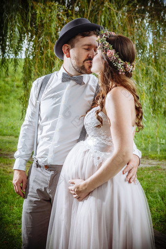 照片怀孕了新娘和新郎接吻在的婚礼仪式