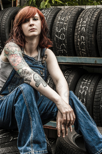 照片年轻的美丽的红色头发的人机械师穿工作服和坐着后面老车库附加财产释放为手臂纹身
