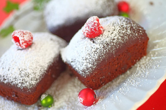 小巧克力蛋糕与新鲜的树莓和粉糖与小圣诞节饰品