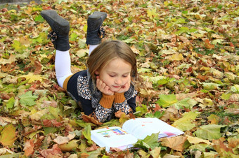 年轻的女孩读取书的秋天公园年轻的女孩读取书的秋天公园说谎的地面