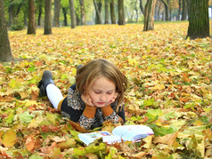 女孩读取书的秋天公园年轻的女孩读取书的秋天公园年轻的女孩读取书的秋天公园说谎的地面