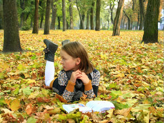 年轻的女孩读取书的秋天公园年轻的女孩读取书的秋天公园说谎的地面
