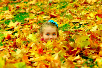 小女孩隐藏自己黄色的叶子的公园小女孩隐藏自己黄色的叶子的秋天公园