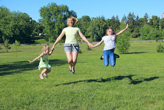 快乐妈妈。有有趣的跳与她的女儿绿色草快乐家庭团队家庭享受夏天假期人享受家庭假期快乐妈妈。有有趣的跳与她的女儿绿色草
