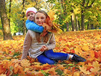 年轻的漂亮的姐妹坐和拥抱黄色的叶子秋天公园小蔡尔兹与秋天叶子小女孩秋天森林秋天的情绪秋天的走快乐童年年轻的漂亮的姐妹坐和拥抱黄色的叶子秋天公园