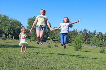 快乐妈妈。有有趣的跳与她的女儿绿色草快乐家庭团队家庭享受夏天假期人享受家庭假期快乐妈妈。有有趣的跳与她的女儿绿色草
