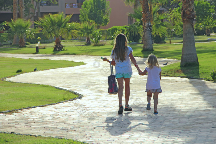 小游客路度假胜地小镇持有手手两个小姐妹会路径在棕榈树年轻的女孩享受夏天假期孩子们放松概念小游客路度假胜地小镇持有手手放松概念