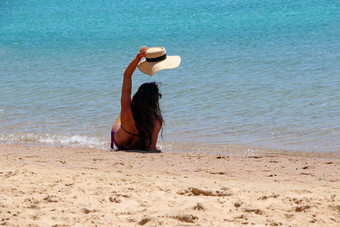 年轻的女人坐着桑迪海滩海和挥舞着他女人享受<strong>夏天</strong>假期海边女旅游日光浴和放松海滩在<strong>夏天</strong>假期女旅游日光浴和放松海滩在<strong>夏天</strong>假期