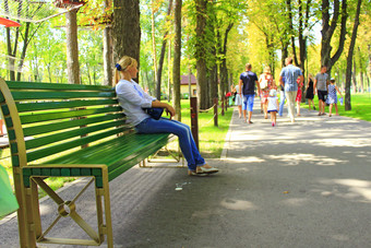 年轻的女人坐着板凳上美丽的公园与许多绿色树女人放松板凳上美丽的夏天公园夏天公园与的地方为休息有吸引力的女孩坐着公园板凳上年轻的女人坐着板凳上美丽的公园与许多绿色树