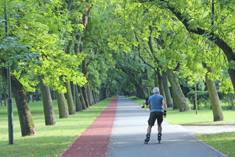 美丽的城市公园与跑步机和男人。运行辊溜冰鞋老男人。运行辊溜冰鞋城市公园城市自然健康的生活方式美丽的城市公园与跑步机和男人。运行辊溜冰鞋