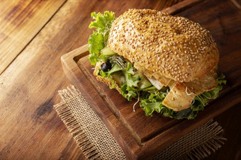 健康的自制的三明治与烤奇肯乳房生菜鳄梨苜蓿细菌和各种各样的其他蔬菜乡村木董事会