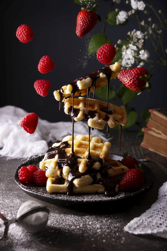 有创意的图像自制的华夫饼悬浮与液体巧克力水果和粉糖黑暗菜darkfood悬浮照片