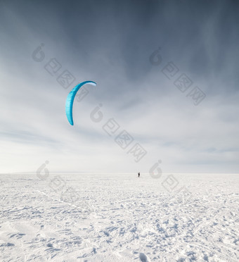 风筝冲浪者被拉他的风筝在的雪风筝冲浪者与蓝色的风筝的雪