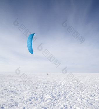 风筝冲浪者被拉他的风筝在的雪风筝冲浪者与蓝色的风筝的雪