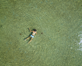 的空中视图游泳女人水夏天海景与女孩清晰的Azure水波日出透明的水前视图从飞行无人机空中视图游泳女人水夏天海景与女孩清晰的Azure水波日出透明的水前视图从飞行无人机