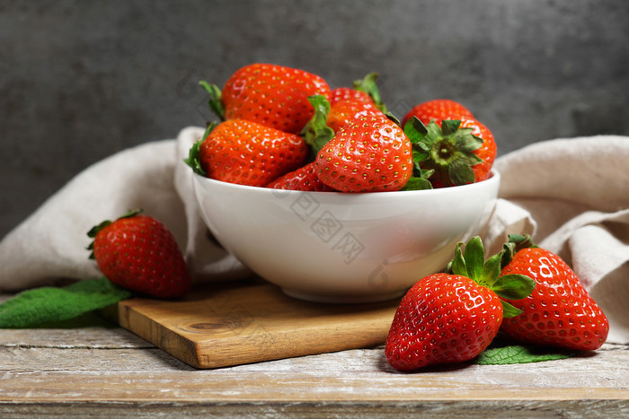 草莓概念与集团成熟的红色的草莓白色碗关闭额视图古董乡村木表格和灰色背景