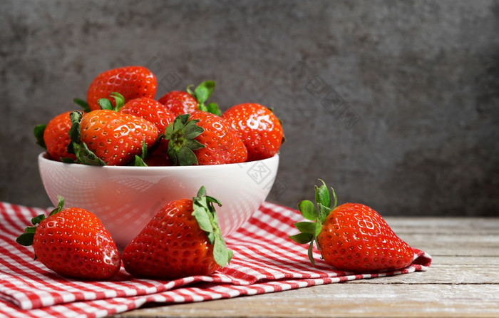 草莓概念与集团成熟的红色的草莓白色碗关闭额视图古董乡村木表格和黑暗灰色背景