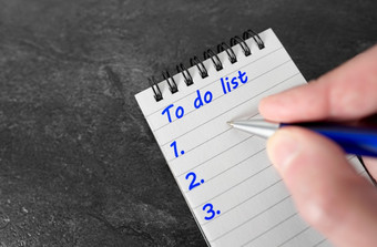 列表业务计划概念与特写镜头手写作工作任务命令列表与蓝色的笔笔记本黑暗灰色表格背景