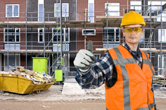 满意看建设工人给竖起大拇指前面巨大的住宅建筑网站