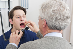 一般医生检查口而且喉咙病人与喉炎