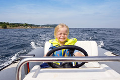 年轻的男孩后面的操舵轮充气快艇