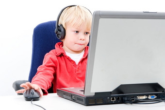 年轻的男孩坐着后面移动PC<strong>点击</strong>computermouse同时看的<strong>屏幕</strong>而且穿耳机