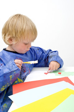 孩子停滞,块彩色的纸使用刷与胶水