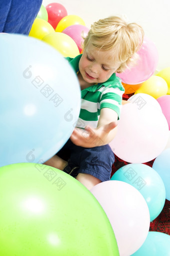 年轻的男孩<strong>坐</strong>着的地板上玩与<strong>气球</strong>