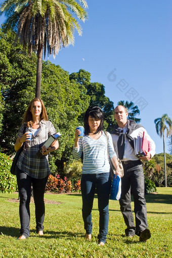 <strong>三个</strong>大学学生走通过的公园他们的道路大学美丽的阳光明媚的早....