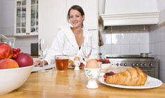 年轻的女人享受丰富的早餐厨房计数器与水果羊角面包鸡蛋而且的早....纸
