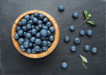 新鲜的蓝莓与叶子碗黑暗石头<strong>背景</strong>平躺前视图