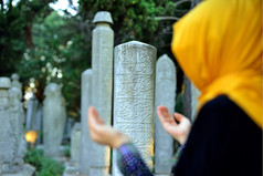 蒙着面纱女人祈祷前面的老墓碑