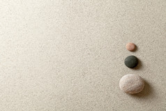 三个色彩斑斓的zen石头正确的一边沙子背景