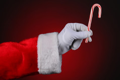 圣诞老人老人手持有糖果狗在红色的光黑暗背景水平格式显示手而且手臂只有