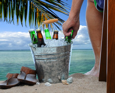 特写镜头男人。坐着椅子热带海滩达到成桶填满与冰冷啤酒只有的男人腿而且是是可见