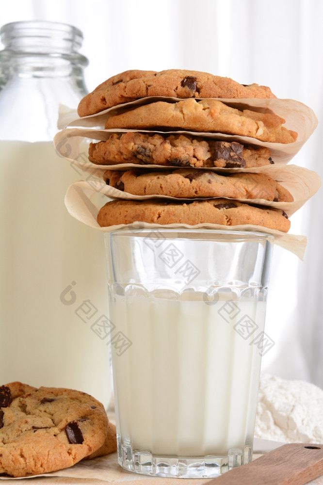 特写镜头堆栈新鲜的烤饼干前玻璃牛奶垂直格式与瓶牛奶而且面粉的背景巧克力芯片燕麦片葡萄干白色巧克力饼干
