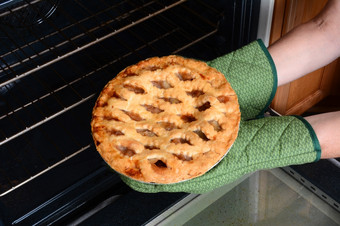 特写镜头女人采取新鲜的烤苹果馅饼从的烤箱苹果馅饼传统的美国沙漠为假期盛宴水平显示的女士手烤箱连指手套只有