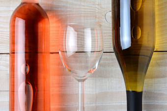 特写镜头酒玻璃之间的瓶红色的酒而且瓶白色酒所有三个对象是铺设乡村白色木表格水平格式从高角