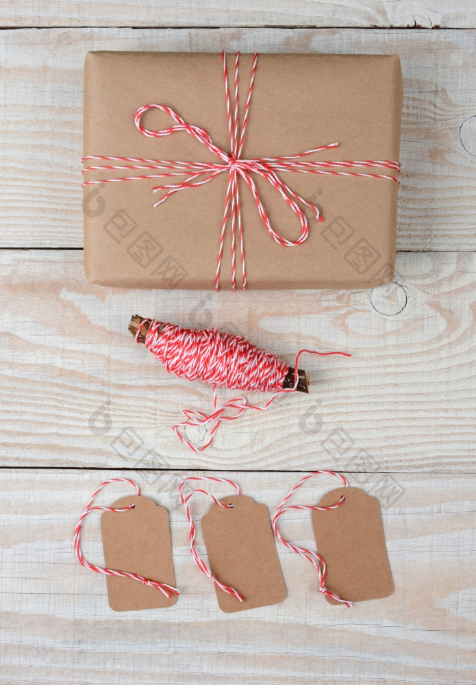 高角拍摄圣诞节包包装平原棕色（的）纸而且系与红色的而且白色字符串三个空白标签而且线轴字符串是下面的礼物白色乡村表格