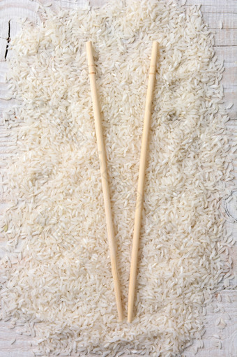 高角特写镜头拍摄木筷子铺设床上未煮过的白色大米的粮食传<strong>播出</strong>乡村木表格垂直格式